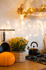 Fototapeta na wymiar Autumn kitchen interior. Red and yellow leaves and flowers in the vase and pumpkin on light background