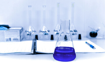 A glass flask with a lilac reagent stands on a table in the laboratory.