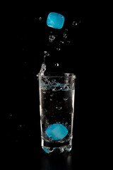 Glass of water filled with blue ice cubes