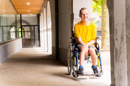 Portrait Of A Disabled Person In A Wheelchair Smiling Next To Some Columns In A Doorway