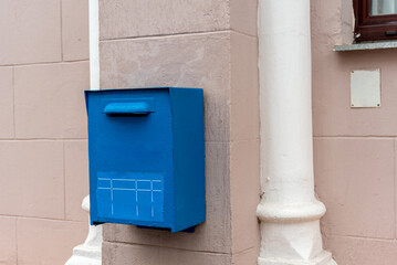 Blue post box on a building wall in the city