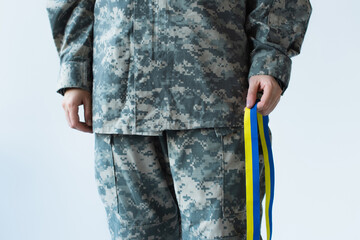 Cropped view of servicewoman holding blue and yellow ribbon isolated on grey