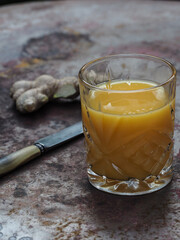 Hot mulled wine decorated with orange and ginger on an old red lacquered metal table with ginger and knife in the background