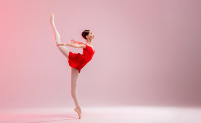 Beautiful young ballerina on a white background. The ballerina is dressed in a red leotard, pink leotards, pointe shoes. - obrazy, fototapety, plakaty