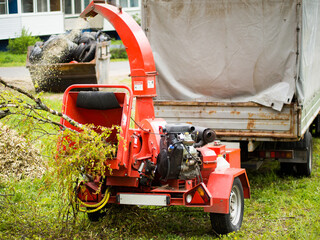 Mobile wood and branch shredder in the city park. Agricultural machinery, wood chipping machine