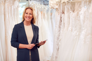 Portrait Of Owner Of Bridal Wedding Dress Shop With Digital Tablet