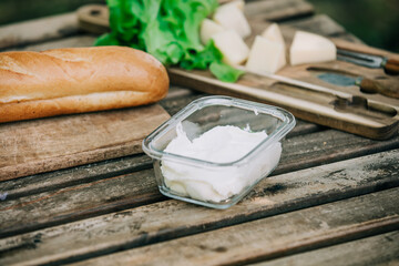 Jar with a cream cheese and bread on wooden table in outdoor
