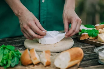 Foto op Canvas Stylish woman in green shirt make a snack with bread and cheese on a table in outdoor © Masson