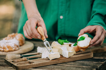 Stylish woman in green shirt stabs cheese snack with a fork