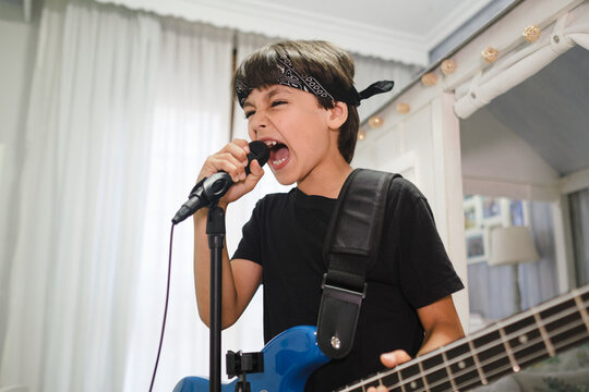 Young child with a bandana giving a rock concert at home.