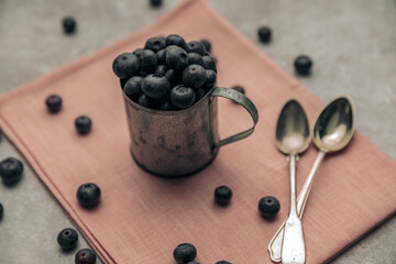 metal cup of blueberries illustrating abundance concept with spoons near