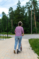 Rear view selective focus on a woman in a striped t-shirt, who is resting in a park near the...