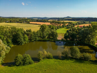 Pond, field, meadow, castle Trosky in Czech paradise in summer from drone. - 520553782