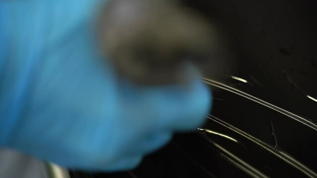 Close-up view of a tattoo artist sticking the tattoo machine into a vaseline gel.