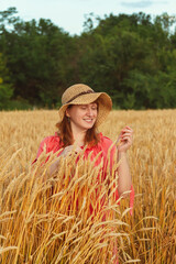 Obraz premium A woman in the evening in a wheat field examines the ears
