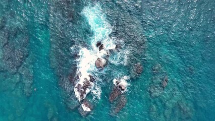 Aerial slow-motion of blue sea waves hitting the cliffs
