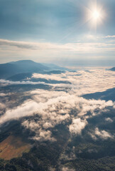 Amazing aerial view of beautiful low clouds creeping on the tree-covered mountain slopes, the Rhodopes in Bulgaria at sunrise.
