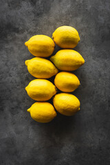 vista superior de dos filas de limones sobre un fondo gris oscuro