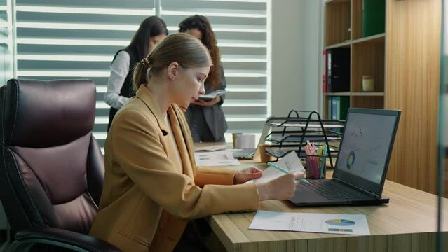 Executive manager taking notes on financial documents to create data charts with sales statistics. Accountant analyzing research papers and report on laptop for business development.