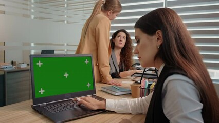Businessman working on a laptop with green screen on background colleague discussing details. Modern office. - Powered by Adobe
