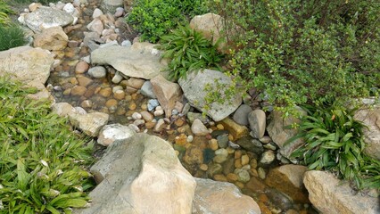 Garden brook surrounded by boulders and greenery