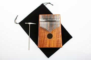 Musical instrument kalimba with a small metal hammer for tuning on a white background