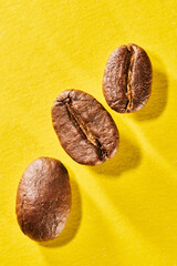 Roasted coffee beans isolated close up on yellow background, clipping path