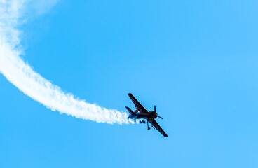 Silhouettes of training aircraft performing aerobatics on a clear sunny day.
