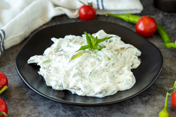 Fresh yoghurt appetizer. Dry tzatziki on a dark background. Cacik made with mint, salad and yogurt. Healthy meals. Local name kuru cacik .Close up