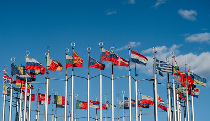 Fototapeta na wymiar flags of the countries of the world on flagpoles against the blue sky on a sunny day