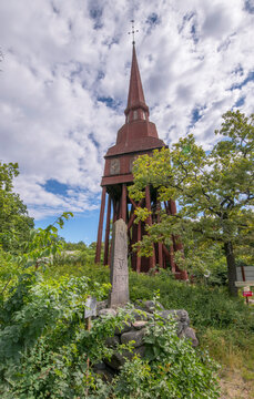 Old road distance stone, milsten and a clock red wood steeple, a sunny summer day in Stockholm