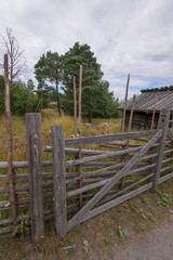 An old wood fence, gärdsgård, at a meadow and log shed, a sunny summer day in Stockholm