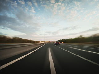 Speedy road drive along the countryside highway. Front view from the car window to the road, other vehicles and surrounding landscapes.