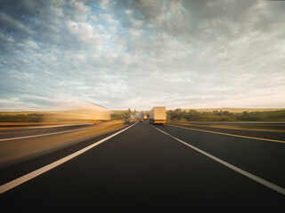 Beautiful shot of a fast drive along the countryside highway. Front view from the car window to the road, other vehicles and surrounding landscapes.
