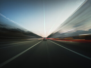 Speedy road drive along the evening highway. Front view from the car window to the road and other vehicles with beautiful light trails.