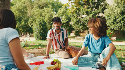 Happy smiling young multinational people at picnic on summer day outdoors. Friends have fun weekend...