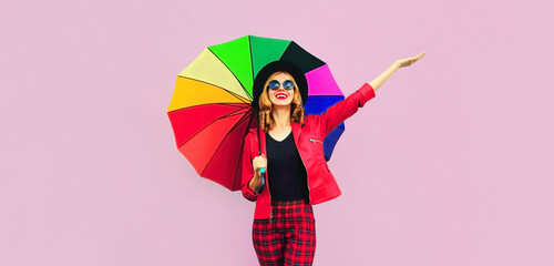 Autumn portrait of happy smiling young woman holding colorful umbrella wearing jacket on background