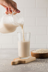 Vegetable rice milk is poured from a jug into a glass. Alternative milk.