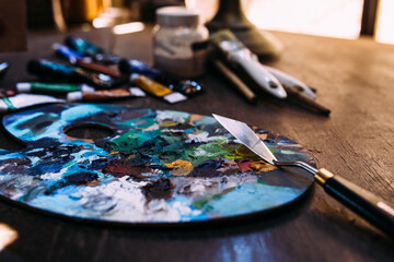 Palette in paint and a palette knife on a wooden table.