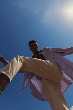 bottom view of african american man posing in trendy summer clothes under blue sunny sky