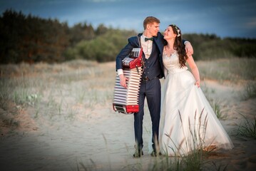 Beautiful shot of a young romantic bride and a groom with an accordion posing