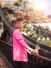 Young woman tourist standing with glass of white wine at bridge in european city , river at background
