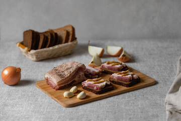 rustic natural food, on a linen tablecloth a wooden board, on it is black rye bread with salted bacon and mustard and boiled eggs.