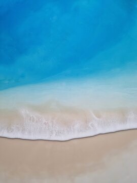 Summer sandy beach drawing by epoxy resin. Top view on ocean wave with white foam, sea wave background , beach screensaver 