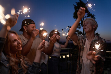 Group of friends celebrating together at the rooftop with sparkles