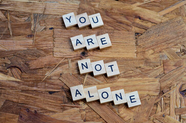 you are not alone text on wooden square, motivation quotes