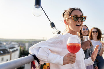 Caucasian young woman with cocktail at the rooftop party