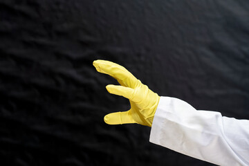 A doctor in a medical gown and protective gloves threatens with an open palm. The face is not visible.