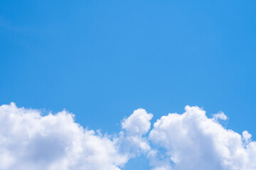 Background with a frame of white cumulus clouds and empty space for text on a blue background.