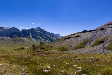 Fototapeta na wymiar Aerial view towards the high mountains of the Greina plateau in Blenio, Swiss Alps. A rocky ridge on the right leads the eye towards the hilly valley. 